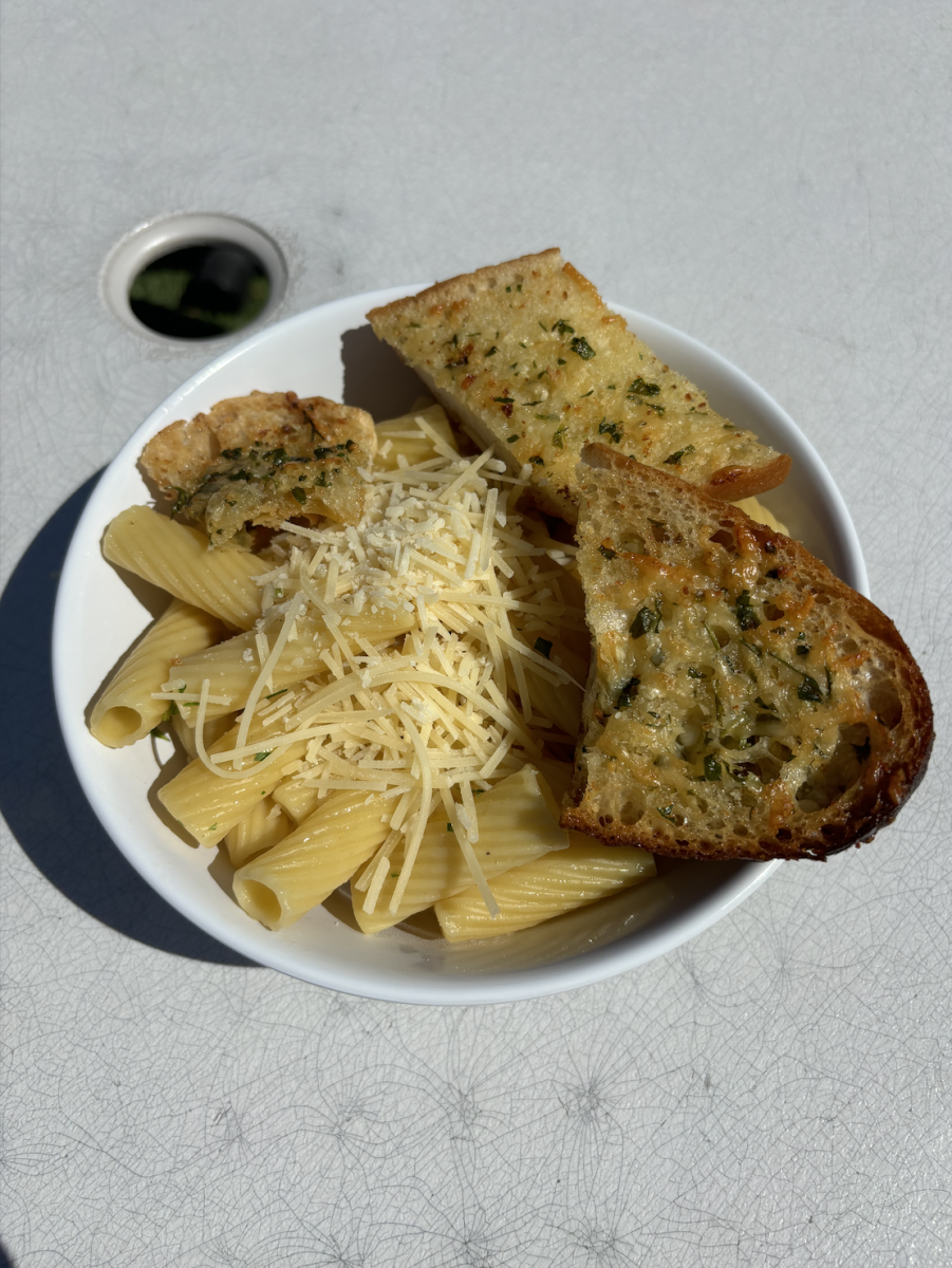 Pasta lunch topped with cheese and a side of garlic bread. 